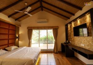 a bedroom with a bed and a tv and a window at Lotus Hotel & Resort in Ambernath