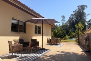 a patio with a table and chairs and an umbrella at Vila Felicia in Cabeceiras de Basto