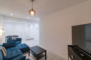 a living room with a blue couch and a flat screen tv at Luna Apartments Ashington in Ashington