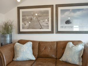 a brown leather couch in a living room with two pictures at Ludlow Bank in Caulderton