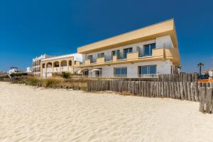 a building on the beach next to a sandy beach at Nella Suites Rooms in Torre Lapillo +7 photos