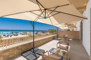 a patio with chairs and an umbrella and the beach at Nella Suites Rooms in Torre Lapillo