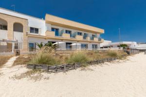 a building on the beach next to the sand at Nella Suites Rooms in Torre Lapillo