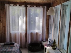 Un dormitorio con una cama y dos ventanas con cortinas. en Mustajärvi, en Konnevesi