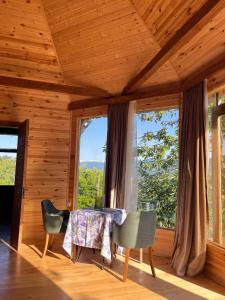 a dining room with a table and chairs and windows at Panoramic Wood Cabin in Itʼkhvisi