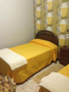 1 dormitorio con 2 camas con sábanas amarillas en Hostal Salones Victoria, en Santa Marina del Rey