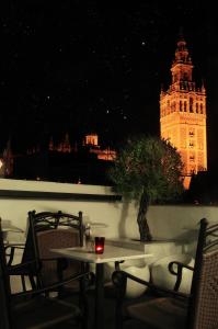 una mesa y sillas con una torre de reloj en el fondo en Hotel Palacio Alcázar en Sevilla