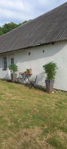 a white building with a table and two plants in a yard at Lägenhet med privat parkering och WiFi i Slättaröd, Torekov in Båstad