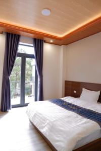 a bedroom with a bed and a large window at Diamond Luxury Hotel & Café Măng Đen in Kon Plong