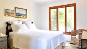 Un dormitorio con una cama blanca y una ventana. en Songbird Sojourn, en Cape May Point