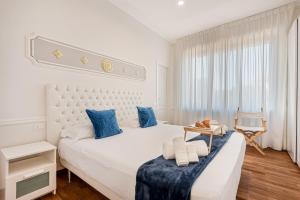 une chambre blanche avec un grand lit avec des oreillers bleus dans l'établissement GOLDEN LUXE - Seafront Terrace next to the Beach, à Marina di Pietrasanta