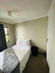 a bedroom with a bed with white sheets and pillows at Lala Properties in Bloemfontein