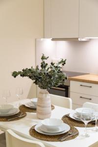 a table with white plates and a vase with a plant at Elea in Mytilene