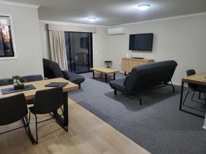 Una sala de espera con sillas y mesas y un televisor. en Noosa Holiday Accommodation, en Noosaville