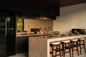a kitchen with black cabinets and a counter with bar stools at The Placo Villa Uluwatu in Denpasar