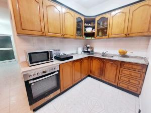 a kitchen with wooden cabinets and a microwave at D Friendship Apartment in Shkodër +5 photos
