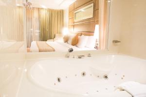 ein Bad mit einer Badewanne und ein Schlafzimmer in der Unterkunft Intimate Hotel Pattaya - SHA Extra Plus in Pattaya