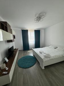 a white bedroom with a bed and a blue rug at Jazz Residence 2 in Piatra Neamţ