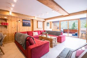 un soggiorno con un divano rosso e un tavolo di Chalet Vithos - Luxe, ski aux pieds a Les Bruyères