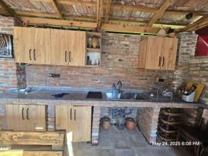 a kitchen with wooden cabinets and a brick wall at Lili's Riverside Villa in Dagva in Zeda Dagva