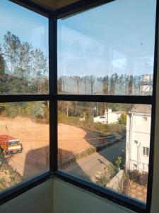 a window with a view of a field and a truck at LTP Resort inn yercaud in Yercaud