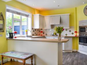 a kitchen with yellow walls and white cabinets at Number Three in Bridlington