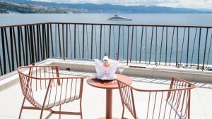 a table and chairs on a balcony with a view of the water at Amadria Park Grand Hotel 4 Opatijska Cvijeta in Opatija