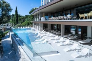 a hotel with a swimming pool and white chairs at Amadria Park Grand Hotel 4 Opatijska Cvijeta in Opatija
