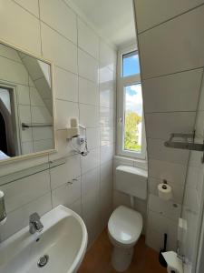 a bathroom with a sink and a toilet and a window at Hotel Monopol in Hilden +27 photos
