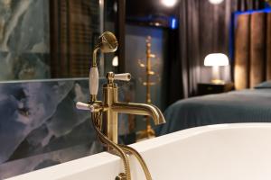 a bathroom sink with a brass faucet next to a tub at La Suite Versailles freeParking table massage Clim in Montreuil
