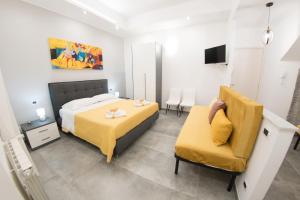 a bedroom with a bed and a yellow chair at Affittacamere SANT'ANNA in Caltagirone
