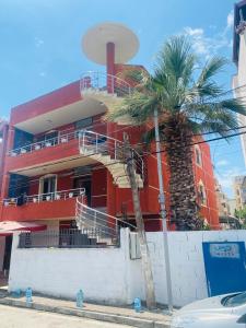 a red building with a palm tree in front of it at Vacation house villa roni in Durrës +8 photos