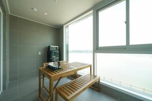 a room with a bench and a television and a window at Hotel Opus in Gyeongju