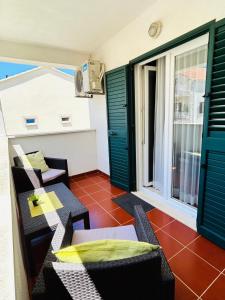 a balcony with chairs and a table and a window at Guest House Sol 1 in Cavtat