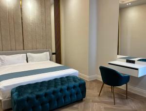 a bedroom with a large bed and a blue tufted chair at Muras Residence Hotel in Bishkek
