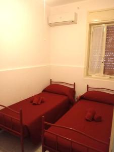 2 posti letto in una camera con lenzuola rosse e finestra di oasis home a Reitani