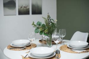 a dining room table with white plates and wine glasses at Central - Green - Stylish - Quiet Sleep in Debrecen