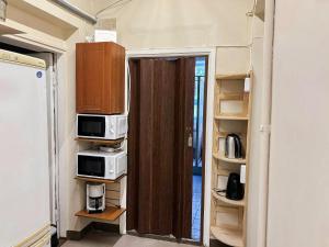 a room with two microwaves and a door with shelves at UKU Villa in Tallinn