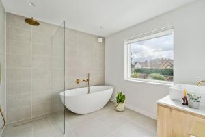 a bathroom with a tub and a glass shower at Glade House in Marlow +12 photos