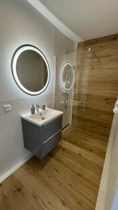 Un baño con lavabo, espejo y ducha. en ANNA rooms and apartments, en Mielno
