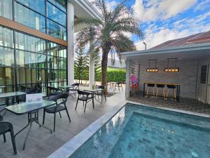 an outdoor patio with tables and chairs and a swimming pool at Theessence hotel chanthaburi in Ban Noen Sung