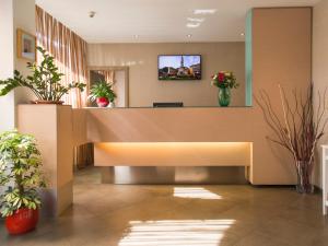 an office lobby with a reception desk and potted plants at Hotel Regina in Bolzano