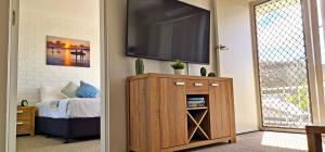 a living room with a tv on a wall at 85 on First - Sawtell Apartments in Sawtell