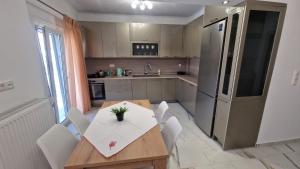 a kitchen with a wooden table and white chairs at Aegean Horizon Apartment in Skala Marion