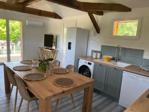 cocina con mesa de madera con sillas y fregadero en Airial landais, en Mimizan