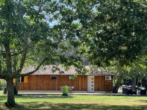 una casa de madera con una valla y un árbol en Airial landais, en Mimizan