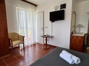 a hotel room with a bed and a chair and a television at Guest House Sol in Cavtat