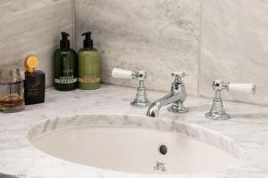 a white bathroom sink with two bottles of wine at Acorn Cottage in Colyton +10 photos