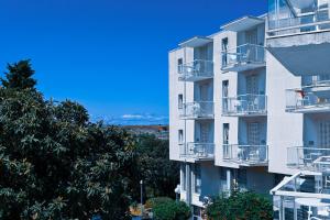 a white apartment building with balconies and trees at Hotel Adriatic in Omišalj