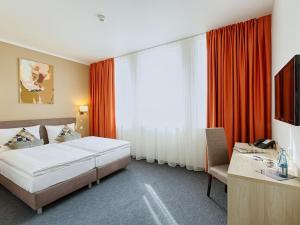 ein Schlafzimmer mit einem Bett, einem Schreibtisch und einem Fernseher in der Unterkunft BO Hotel Hamburg in Hamburg